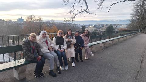 Group of people sitting on a bench overlooking a cityscape.