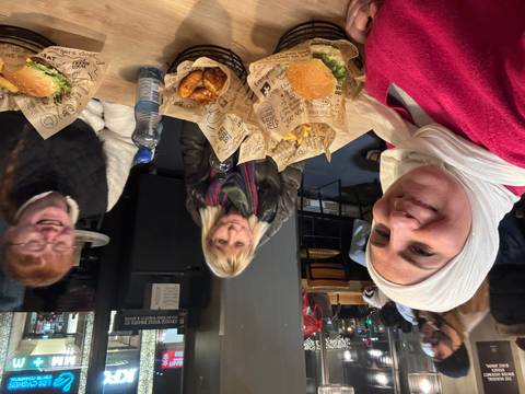 Three people eating burgers at a restaurant.