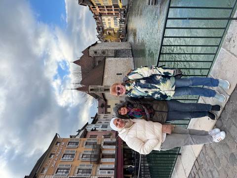 Three people posing in front of a medieval building.