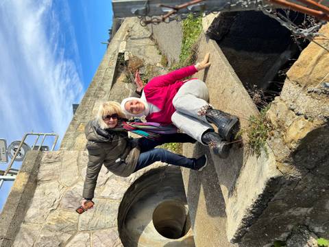 Two women posing on a stone ledge.