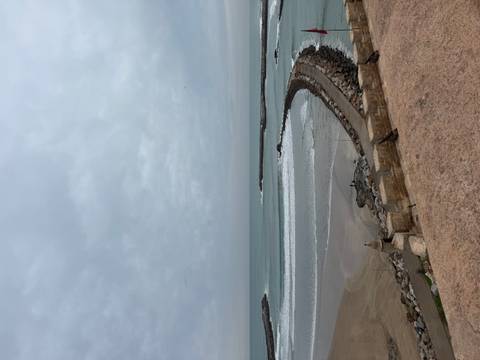 Coastal view with rocky barrier and ocean waves.