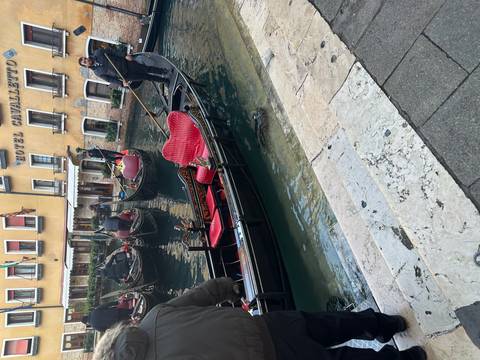 Gondolas in a Venice canal with people on board.