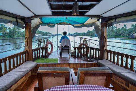 View from the back of a houseboat cruising on a river.