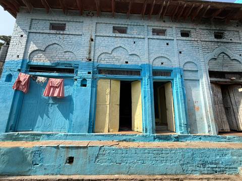 Blue-painted building with ornamental details in a rural setting.