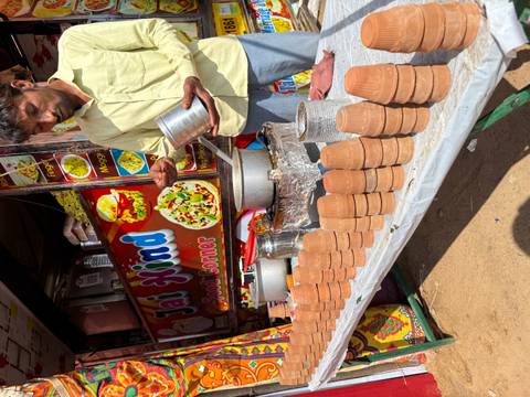 Vendor selling traditional clay cups at a food stall.