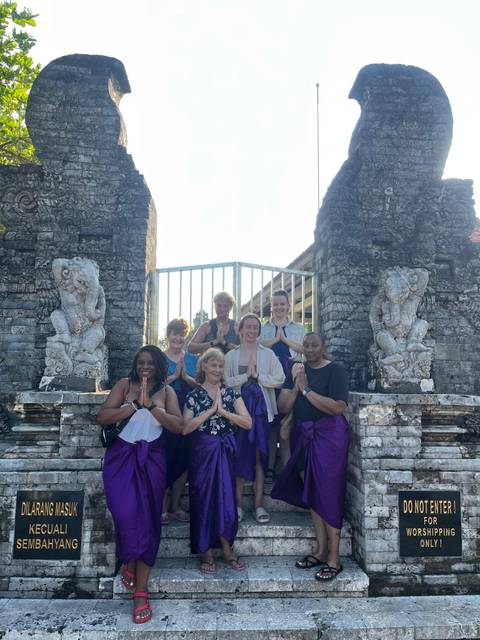 Group posing in front of a traditional gate with stone carvings.
