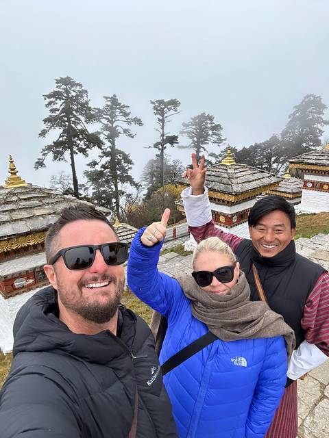 Group of people posing with traditional structures in the background.
