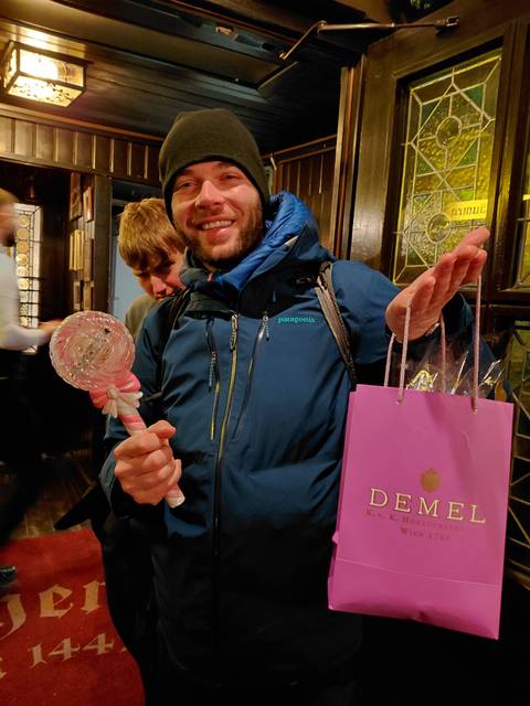 Man holding a gift bag and large candy-like object.