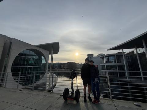 Two people with Segways in front of sunlit government buildings.