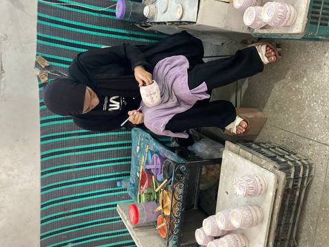 Person painting a ceramic pot with careful attention.
