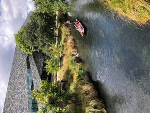 People riding a punt on a narrow stream in a city setting.
