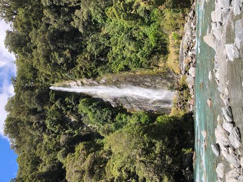 Tall waterfall cascading down a rocky cliff surrounded by forest.