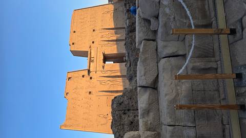 Ancient Egyptian temple with large stone walls and hieroglyphics.