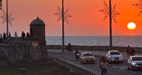 Sunset view with a historic wall and ocean.
