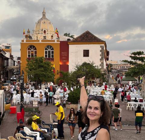 Busy square with colorful buildings and seated people.