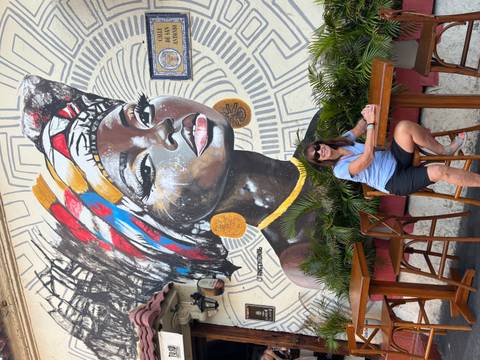 Colorful mural with a woman sitting in front.