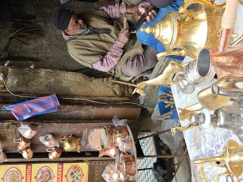 Artisan working with brassware in a Moroccan market.
