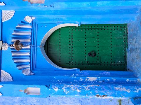 Green door set in a blue wall, typical of Chefchaouen.
