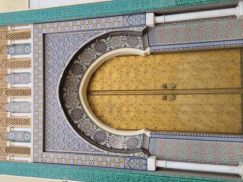 Ornate arched door with intricate tile designs in Morocco.