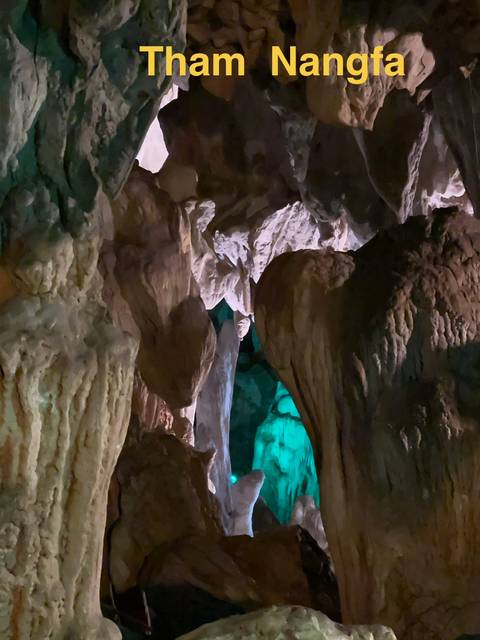 Interior of a cave with stalactites and colorful lighting.