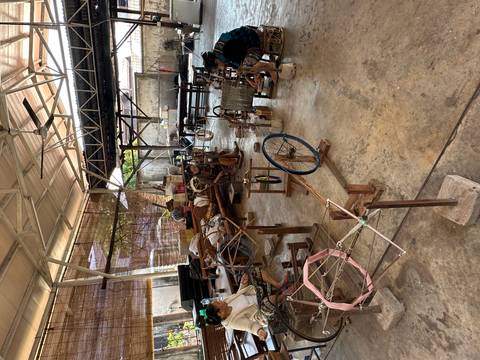 Group of people weaving and working in a traditional workshop.