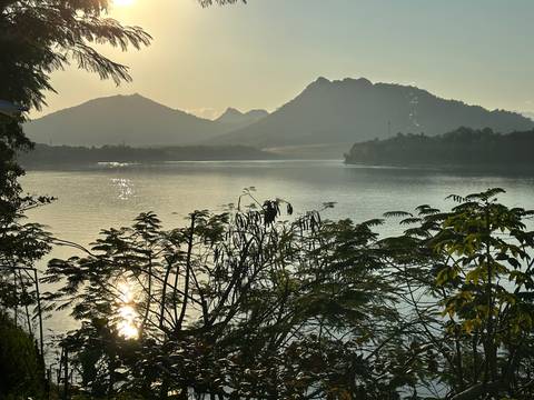 Serene lake surrounded by mountains under a setting sun.