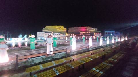 Blurry night scene of a performance with lights and traditional costumes.