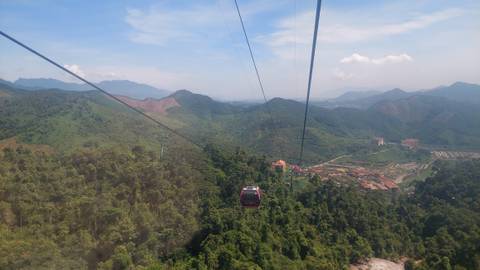 View from a cable car overlooking a vast expanse of greenery and mountains.