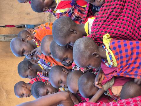 A group of children wearing colorful garments in a village setting.