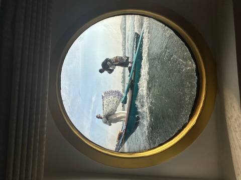 Two people on a boat seen through a round window