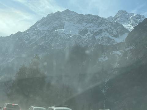Snow-covered mountains with mist and trees in the foreground.