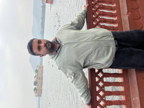 Person standing on a balcony overlooking a lake with a palace in the background.