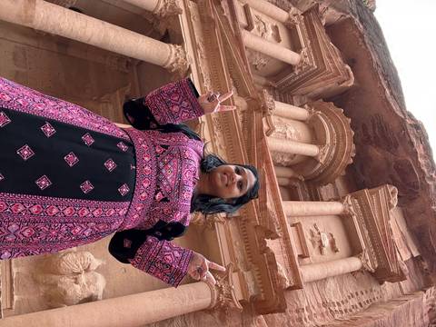 Person posing in front of the carved treasury building in Petra.
