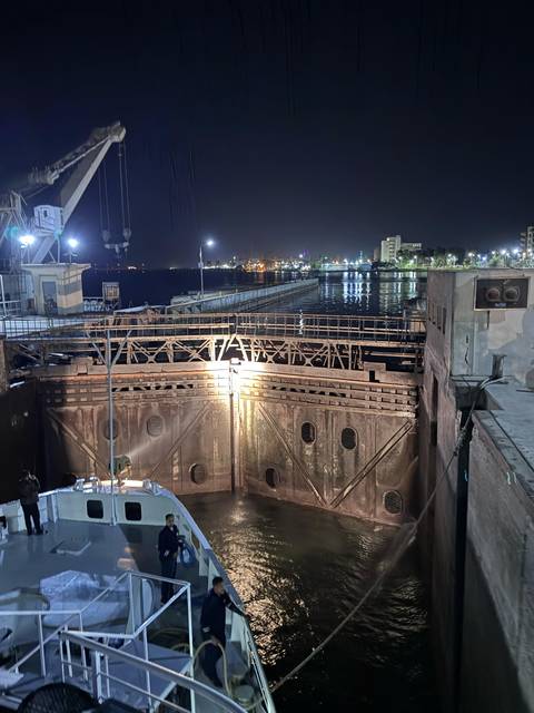 Night view of a canal lock with city lights in the background.