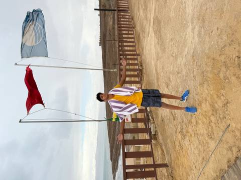 Individual standing in a desert area with flags flying in the wind.