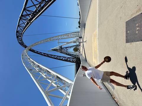 Person posing on a pedestrian bridge with arched structures.