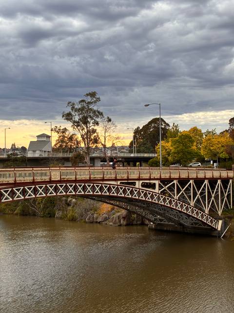 Historic bridge in a park during sunset.