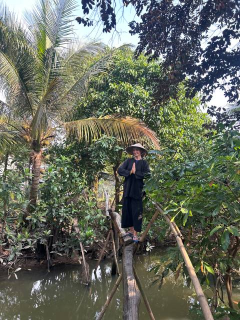 Individual in traditional attire amidst lush greenery.