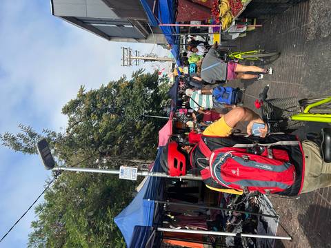 Street market scene with cyclists and market stalls.