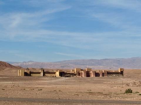 Desert fortress ruins with mountains in the background.