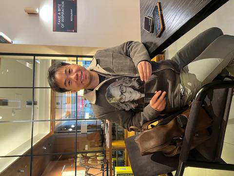 Man sitting in a cafe holding a framed photograph.