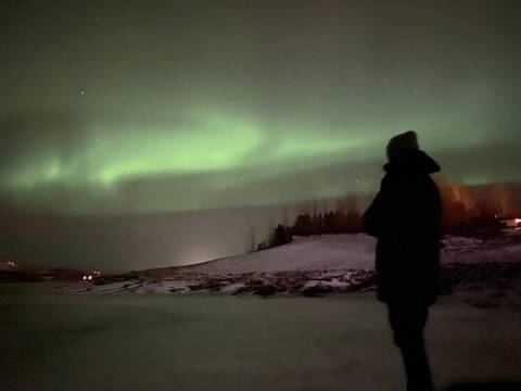 Person silhouetted in front of the Northern Lights.