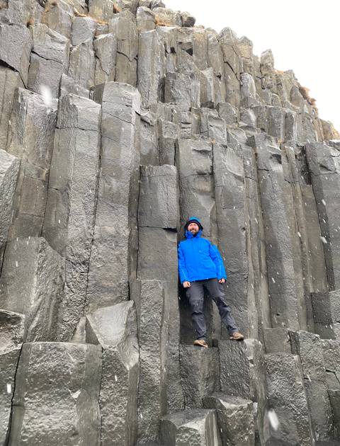 Person posing in front of large, geometric basalt columns.