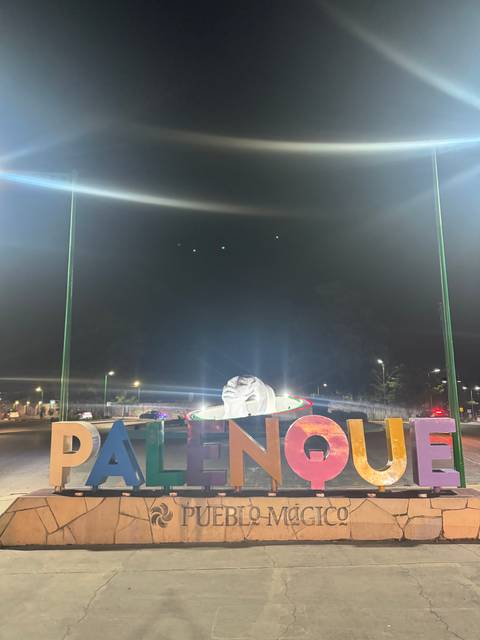 Sculpture of a face with colorful lights at night.