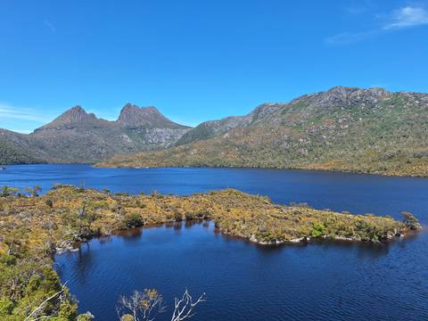 Lake with a mountainous backdrop under a clear blue sky.
