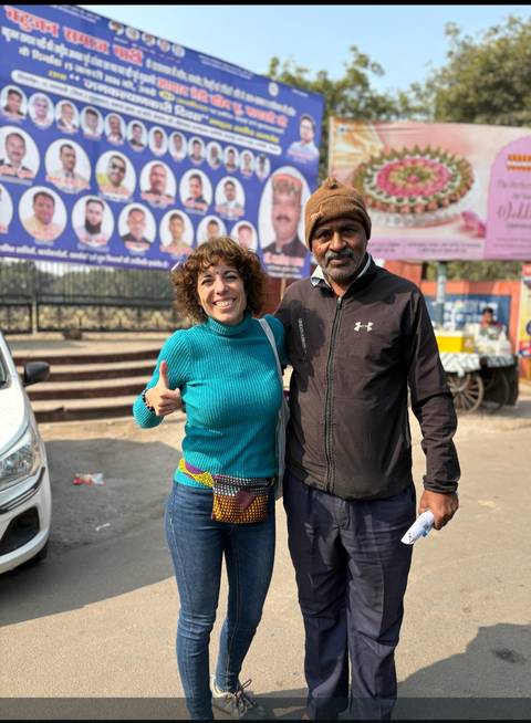 Two people posing happily together in front of outdoor advertisements.