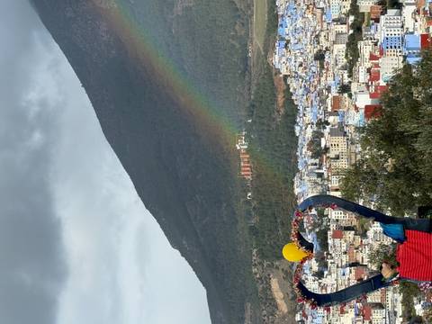 Cityscape with rainbow over mountains and colorful buildings.
