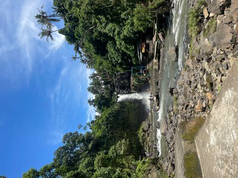 Tourists exploring a waterfall in a lush jungle setting.