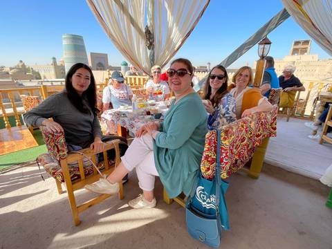 Group of women enjoying a meal at an outdoor restaurant with city views.