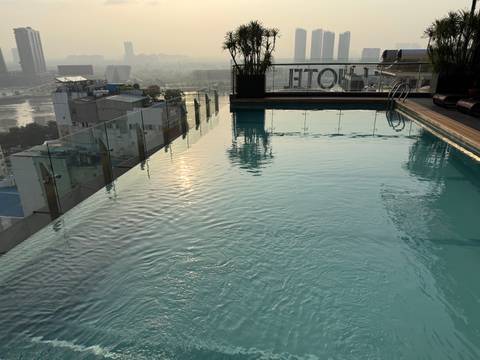 Rooftop infinity pool with city skyline in the background at sunrise.